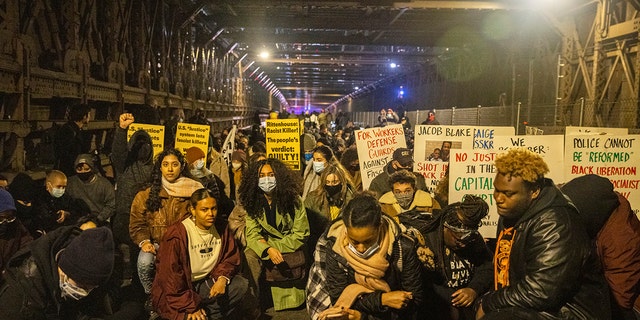 Protests kneel on the Brooklyn Bridge in New York City on Friday night. 