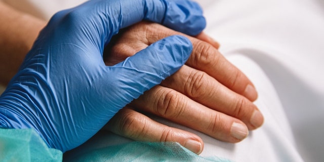 Close up of a doctor hand with blue glove giving support and love to a patient at hospital. Coronavirus pandemic concept.  (Close up of a doctor hand with blue glove giving support and love to a patient at hospital. Coronavirus pandemic concept. , ASC