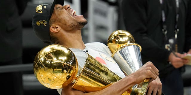 Milwaukee Bucks forward Giannis Antetokounmpo reacts while holding the NBA Championship trophy, left, and Most Valuable Player trophy after defeating the Phoenix Suns in Game 6 of basketball's NBA Finals in Milwaukee, Tuesday, July 20, 2021. The Bucks won 105-98.