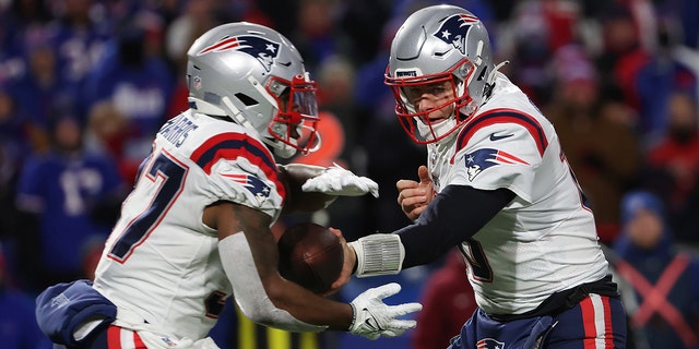 Mac Jones of the New England Patriots hands the ball off to Damien Harris (37) of the New England Patriots during the first quarter against the Buffalo Bills at Highmark Stadium on Dec. 6, 2021, in Orchard Park, New York. 