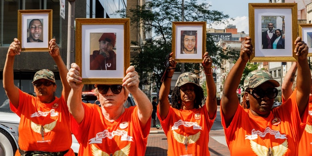 Mothers of Murdered Columbus Children stand at the intersection of High Street and Broad Street while holding pictures of their deceased children. (Stephen Zenner/SOPA Images/LightRocket via Getty Images)