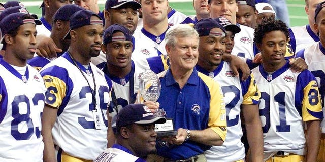 St. Louis Rams head coach Dick Vermeil, center, stands with his team holding the 1999 Staples NFL Coach of the Year award giving to Vermeil before media day, Jan. 25, 2000, at the Georgia Dome, the site of Super Bowl XXXIV in Atlanta. (Getty Images)