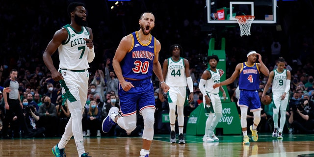 Golden State Warriors guard Stephen Curry (30) reacts after hitting a three point shot as Boston Celtics guard Jaylen Brown (7) looks on during the first half of an NBA basketball game, Friday, Dec. 17, 2021, in Boston.
