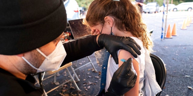 Leah Lefkove, 9, covers her face as her dad Dr. Ben Lefkove gives her the first COVID-19 vaccine at the Viral Solutions vaccination and testing site in Decatur, Ga., on the first day COVID-19 vaccinations were available for children from 5 to 12 on Wednesday, Nov. 3, 2021. (AP Photo/Ben Gray)