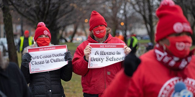 Chicago Teachers Union members display signs while former teacher Tara Stamps speaks ahead of a car caravan where teachers and supporters gathered to demand a safe and equitable return to in-person learning during the COVID-19 pandemic in Chicago, Illinois, on Dec. 12, 2020. 