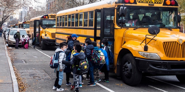 Students wearing masks board a school bus outside New Explorations into Science, Technology and Math school, in the Lower East Side neighborhood of New York, Dec. 21, 2021. (AP Photo/Brittainy Newman, File)
