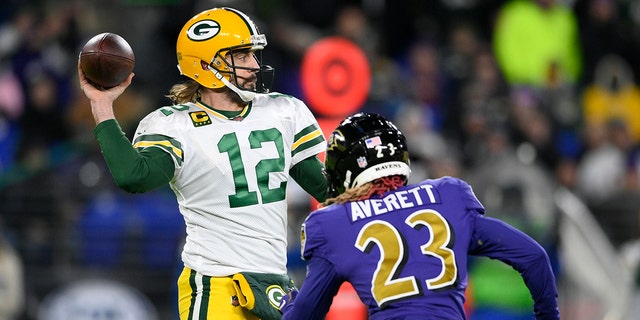 Green Bay Packers quarterback Aaron Rodgers (12) throws to a receiver as he is pressured by Baltimore Ravens cornerback Anthony Averett in the first half of an NFL football game, Sunday, Dec. 19, 2021, in Baltimore.
