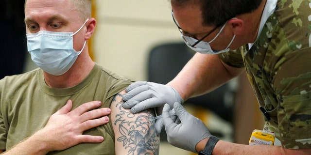 FILE - Staff Sgt. Travis Snyder, left, receives the first dose of the Pfizer COVID-19 vaccine given at Madigan Army Medical Center at Joint Base Lewis-McChord in Washington state, Dec. 16, 2020, south of Seattle. The Army says 98% of its active duty force had gotten at least one dose of the mandatory coronavirus vaccine as of this week’s deadline for the shots. (AP Photo/Ted S. Warren, File) 