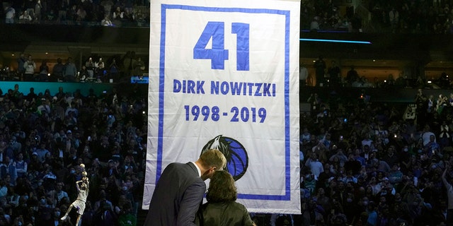 Former Dallas Mavericks Dirk Nowitzki, left, and his wife Jessica Olsson watch a banner being raised during a number retirement ceremony for Nowitzki after an NBA basketball game between the Golden State Warriors and Dallas Mavericks in Dallas, Wednesday, Jan. 5, 2022.