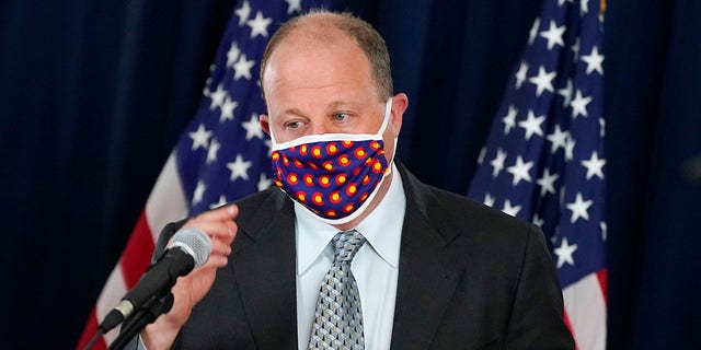 Colorado Gov. Jared Polis wears a face covering as he approaches the podium to make a point about the availability of COVID-19 vaccinations in the state during a news conference on the state's efforts against the coronavirus Tuesday, April 27, 2021, in Denver. (AP Photo/David Zalubowski)