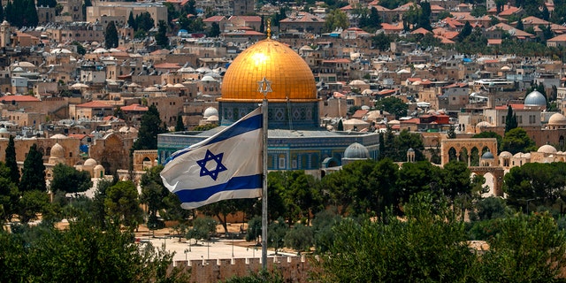 This picture taken on July 30, 2020 from the Mount of the Olives shows a view of an Israeli flag flying in Jerusalem with the Dome of the Rock seen in the background. 