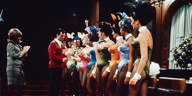 A group of Playboy Bunnies line up for inspection by Hugh Hefner, publisher of Playboy magazine, in the main room of Playboy Mansion in Chicago. Hefner is inspecting the new improved fabric for the costumes.