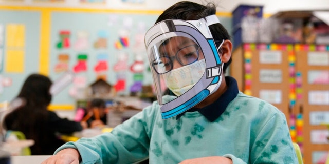 FILE - A student wears a mask and face shield in a 4th grade class amid the COVID-19 pandemic at Washington Elementary School on Jan. 12, 2022, in Lynwood, Calif. Gov. Gavin Newsom delayed a closely watched decision on lifting California's school mask mandate Monday, Feb. 14 even as other Democratic governors around the country have dropped them in recent weeks. (AP Photo/Marcio Jose Sanchez, File) 