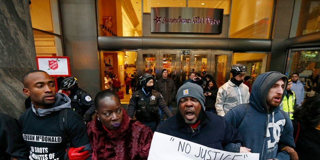 Demonstrators link arms in solidarity as they protest the shooting death of black teenager Laquan McDonald by a white policeman and the city's handling of the case in the downtown shopping district of Chicago, Illinois, November 27, 2015. 