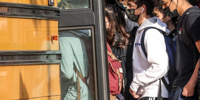 Students board a school bus outside a high school in January. 