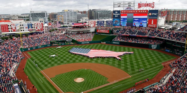 This July 4, 2013, file photo shows a U.S. flag, in the shape of the country, in the outfield before a baseball game between the Washington Nationals and the Milwaukee Brewers at Nationals Park in Washington. Professional sports teams and gambling companies in the U.S. are increasingly bringing the sports book to the game, opening sports betting facilities in or near stadiums. 