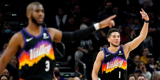 Phoenix Suns guard Devin Booker (1) and guard Chris Paul (3) motion after Booker made a three pointer against the Brooklyn Nets during the second half of an NBA basketball game, Tuesday, Feb. 1, 2022, in Phoenix.