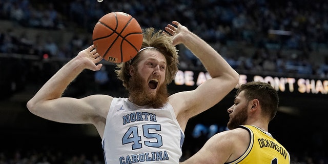 North Carolina forward Brady Manek (45) reacts following a dunk against Michigan center Hunter Dickinson (1) during the first half of an NCAA college basketball game in Chapel Hill, N.C., Wednesday, Dec. 1, 2021.
