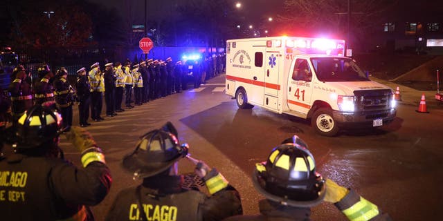 Chicago firefighters and police salute the ambulance carrying the body of Officer Samuel Jimenez outside of the Medical Examiners office at Leavitt and West Harrison streets in Chicago on Nov. 19, 2018.
