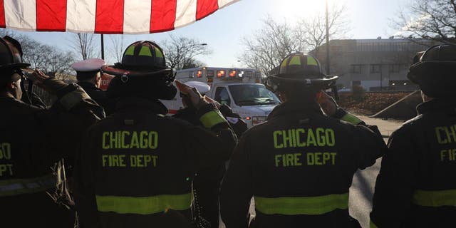 Chicago firefighters salute the ambulance arriving at the Medical Examiners office with the body of an off duty police officer shot and killed in Chicago on Saturday, March 23, 2019.