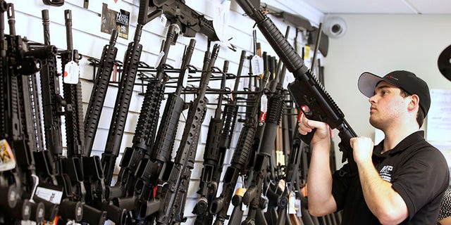 Salesman Ryan Martinez clears the chamber of an AR-15 at the "Ready Gunner" gun store In Provo, Utah.