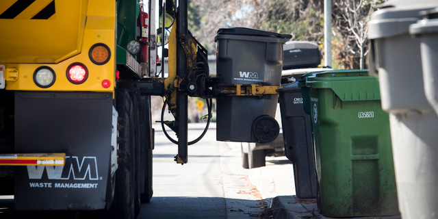 A Waste Management Inc. garbage collection truck empties a trash bin outside a home in Hayward, California, U.S., on Monday, Feb. 12, 2018