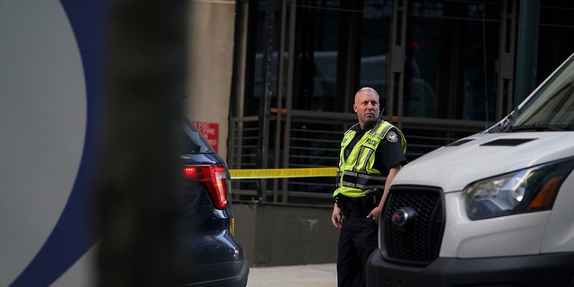 A police officer stands near the entrance of a residential building, Wednesday, Oct. 20, 2021, in Atlanta. (AP Photo/Brynn Anderson)