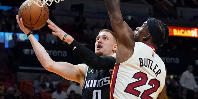 Sacramento Kings guard Donte DiVincenzo (0) drives to the basket as Miami Heat forward Jimmy Butler (22) defends during the first half of an NBA basketball game, Monday, March 28, 2022, in Miami. 