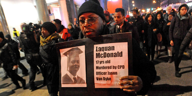 In this Nov. 24, 2015 file photo, a man holds a sign with a photo of Laquan McDonald on it, during a protest of the police shooting 17-year-old McDonald, in Chicago. 