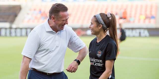Houston Dash head coach James Clarkson smiles while talking to Shea Groom #6 of the Houston Dash before a game between Portland Thorns FC and Houston Dash at BBVA Stadium on July 24, 2021, in Houston, Texas.