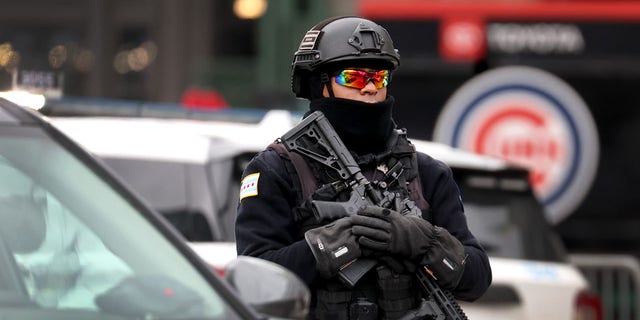 A police officer keeps watch as fans arrive for a chilly home opener at Wrigley Field to watch the Chicago Cubs play the Milwaukee Brewers on April 7, 2022, in Chicago. 