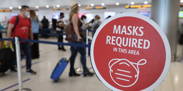 MIAMI, FLORIDA - FEBRUARY 01: A sign reading, 'masks required in this area,' is seen as travelers prepare to check-in for their Delta Airlines flight at the Miami International Airport on February 01, 2021 in Miami, Florida. (Photo by Joe Raedle/Getty Images)