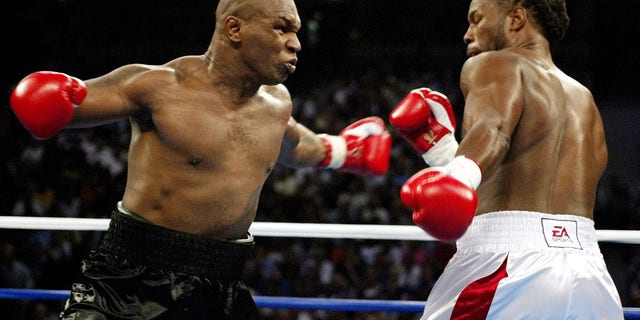 Mike Tyson (L) and Lennox Lewis trade punches during round one of their WBC/IBF/IBO World Heavyweight Championship bout at the Pyramid Arena in Memphis, Tennessee, June 8, 2002.