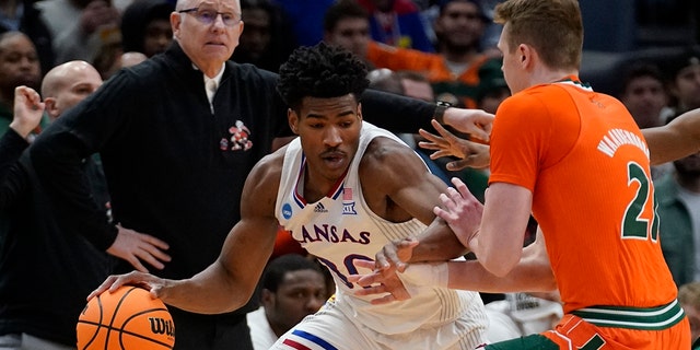 Kansas' Ochai Agbaji tries to get past Miami's Sam Waardenburg during the first half of a game in the Elite Eight of the NCAA tournament March 27, 2022, in Chicago.