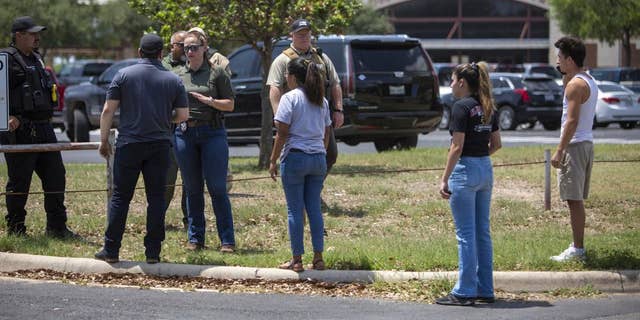 A law enforcement officer speaks with people outside Uvalde High School after shooting a was reported earlier in the day at Robb Elementary School, Tuesday, May 24, 2022, in Uvalde, Texas. 