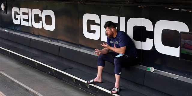 Cleveland Guardians' Bryan Shaw talks on the phone in the dugout after the game between the Chicago White Sox and the Guardians was postponed due to multiple positive COVID-19 tests within the Guardians organization, Wednesday, May 11, 2022, in Chicago.