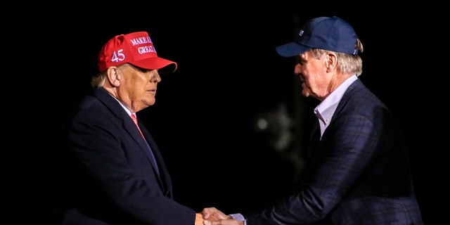 Former President Donald Trump shakes hands with former Sen. David Perdue, who is primary challenging GOP Gov. Brian Kemp of Georgia, at the former president's rally in Cumming, Ga. on March 26, 2022