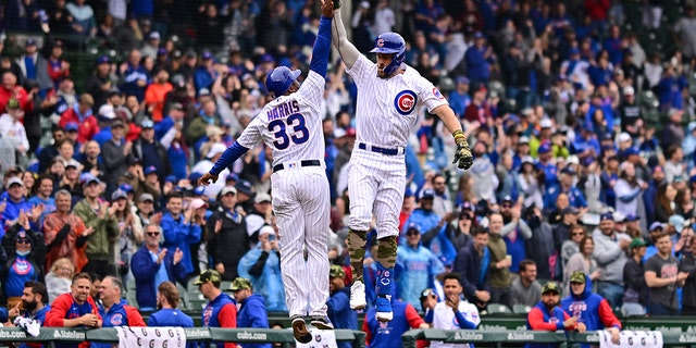 Patrick Wisdom (16) and Willie Harris (33) of the Chicago Cubs celebrate after a home run in the second inning against the Arizona Diamondbacks at Wrigley Field May 21, 2022, in Chicago. 
