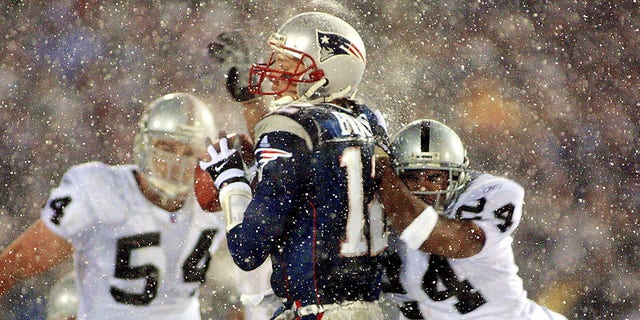 New England Patriots quarterback Tom Brady takes a hit from Charles Woodson of the Oakland Raiders during the AFC playoff game Jan. 19, 2002, in Foxboro, Massachusetts.