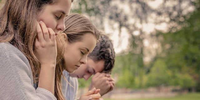 Friends pray together in a park. "We live in a world where bad things will happen. But that shouldn’t stop parents from equipping their kids and working with them to overcome challenging times," said Kathy Koch, PhD.