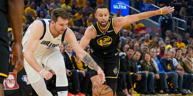 Dallas Mavericks guard Luka Doncic, left, reaches for the ball next to Golden State Warriors guard Stephen Curry (30) during the first half in Game 5 of the NBA basketball playoffs Western Conference finals in San Francisco, Thursday, May 26, 2022. (AP Photo/Jeff Chiu)