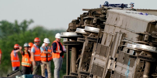 Workers inspect the scene of the Amtrak train that derailed after striking a dump truck Monday, June 27, 2022, near Mendon, Mo. 