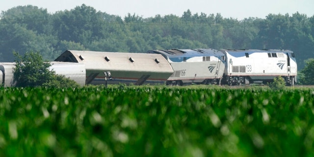 The derailed Amtrak train is seen beyond a cornfield on Tuesday, June 28, 2022, near Mendon, Mo. The train derailed after hitting a dump truck on Monday killing the truck driver and other people on the train and injuring several dozen other passengers on the Chicago-bound train. 