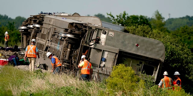 Workers inspect the scene of an Amtrak train which derailed after hitting a dump truck Monday, June 27, 2022, near Mendon, Mo.
