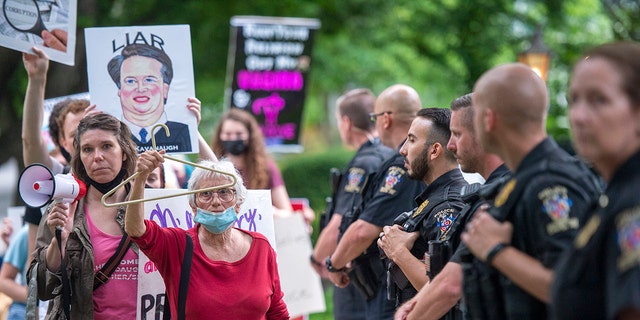 Police officers look on as abortion-rights advocates hold a demonstration outside the home of U.S. Supreme Court Justice Brett Kavanaugh on May 18, 2022 in Chevy Chase, Maryland. 