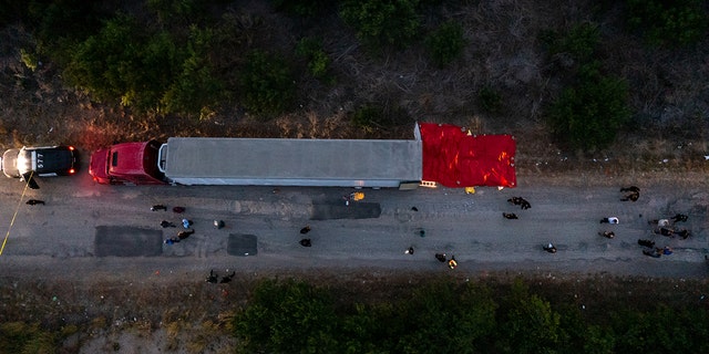 In this aerial view, members of law enforcement investigate a tractor trailer on June 27, 2022, in San Antonio, Texas. Forty-six migrants were found dead in an abandoned tractor trailer, and five more died later. 