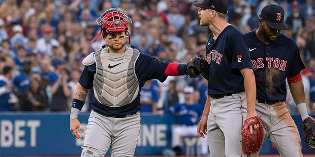 Boston Red Sox catcher Christian Vazquez holds back starting pitcher Nick Pivetta (37) during a heated exchange with the Toronto Blue Jays after Blue Jays' Alejandro Kirk was hit by a pitch during the fourth inning of a baseball game Wednesday, June 29, 2022, in Toronto. 