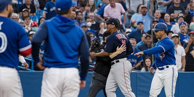 Boston Red Sox third baseman Rafael Devers (11) is held back by an umpire during a heated exchange after Toronto Blue Jays' Alejandro Kirk was hit by a pitch during the fourth inning of a baseball game Wednesday, June 29, 2022, in Toronto. 