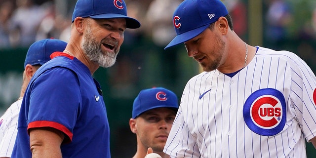 Chicago Cubs manager David Ross, left, smiles as he talks with relief pitcher Mark Leiter Jr., after Mark Leiter Jr., replaced starting pitcher Alec Mills during the first inning of a baseball game against the Boston Red Sox in Chicago, Saturday, July 2, 2022.