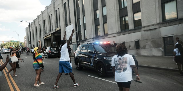 Demonstrators wave signs around a police car as they gather outside Akron City Hall to protest the killing of Jayland Walker, shot by police, in Akron, Ohio, July 3, 2022. 